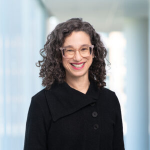 Person with curly hair, glasses and wearing a black shirt