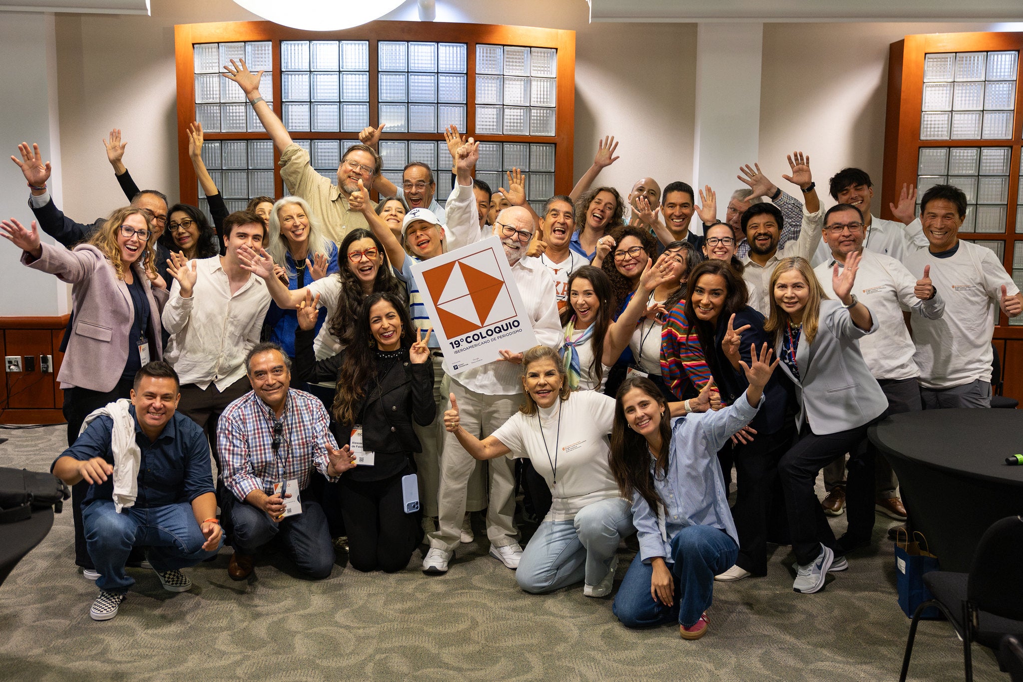 A group of people raise their hands and smile for a photo.